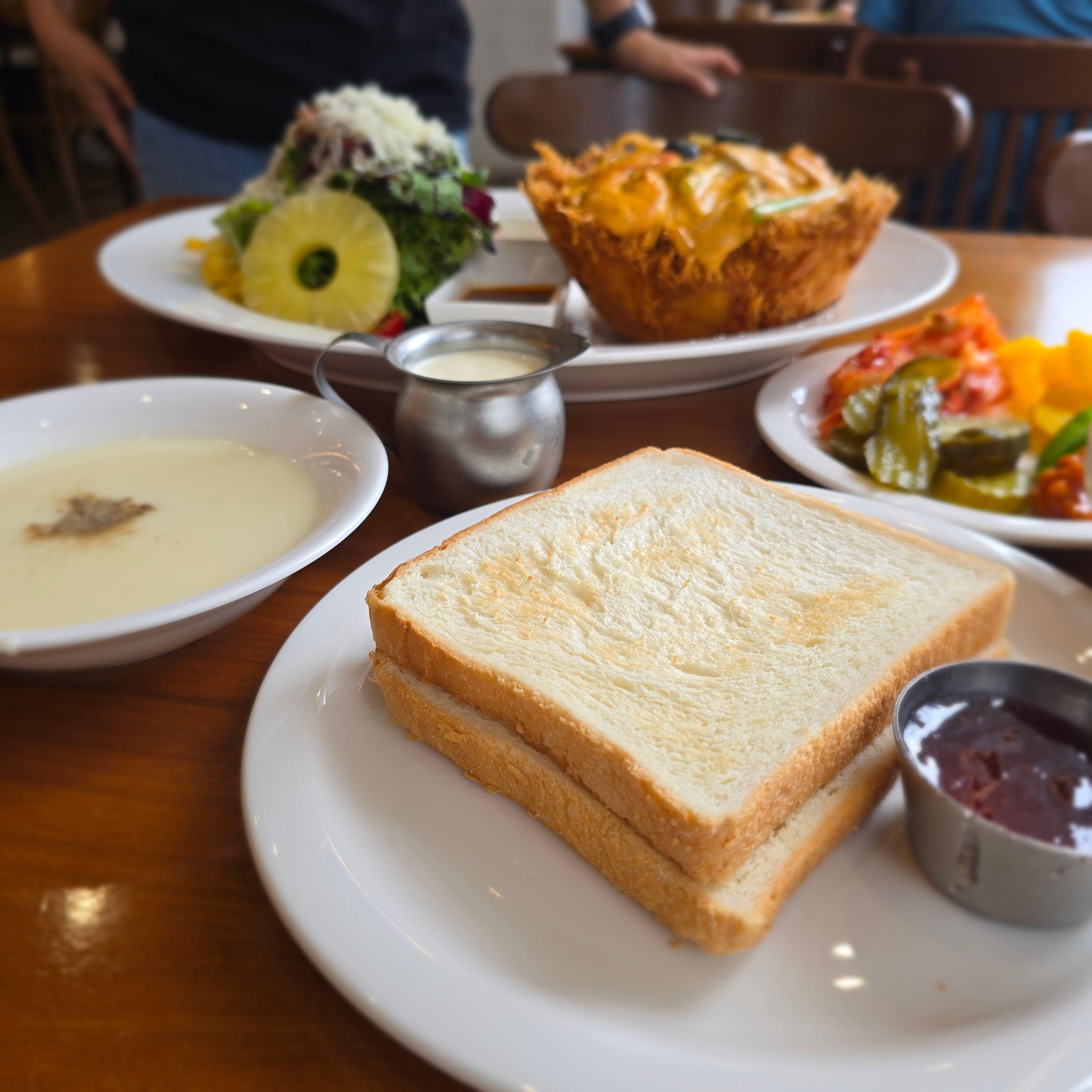 수프, 식빵, 딸기쨈, 샐러드, 돈까스가 놓인 차려진 테이블