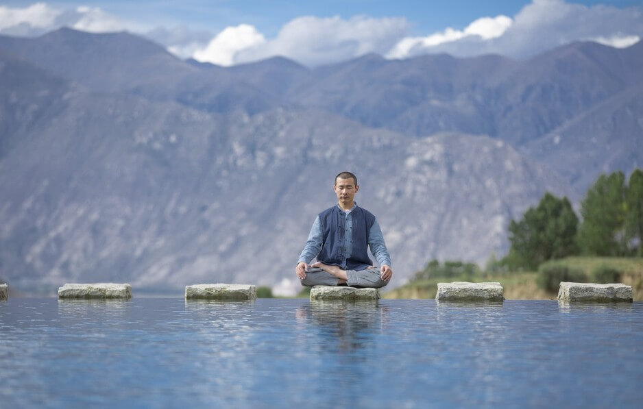 강물 사이에서 명상 중인 남성