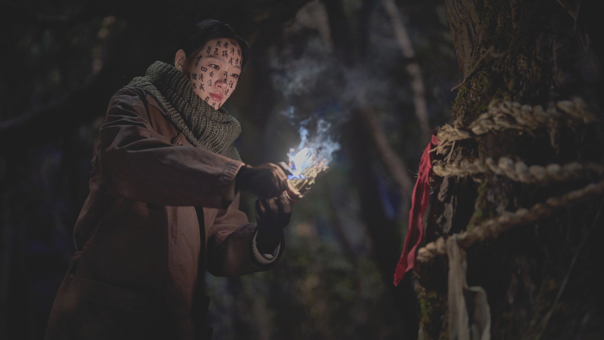 영화 파묘 얼굴에 금강경을 쓴 화림이 나무 앞에서 불을 붙이는 장면 거대한 오니와 맞서는 픽션 연출