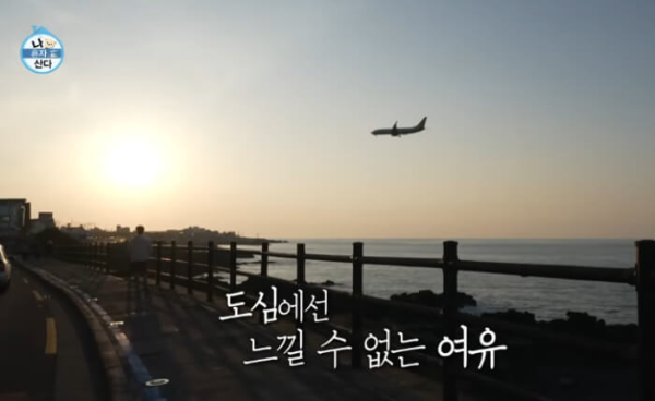 나혼자산다 카이가 해가 져가는 제주 바다를 배경으로 걷고 있다.