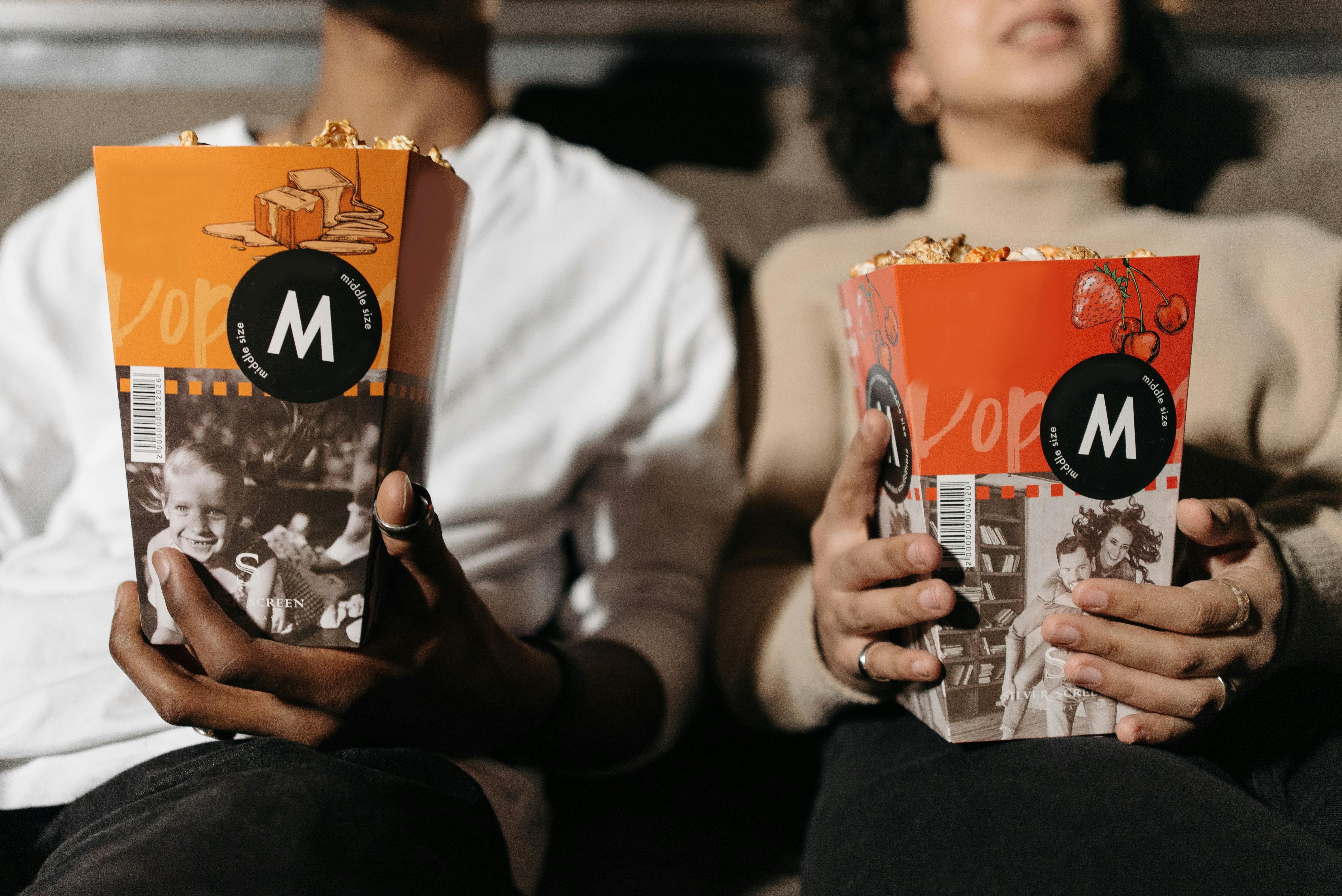 Two people sitting on a couch with popcorn, watching a Korean drama on TV &mdash; representing the global popularity of 16-episode K-dramas on Netflix.