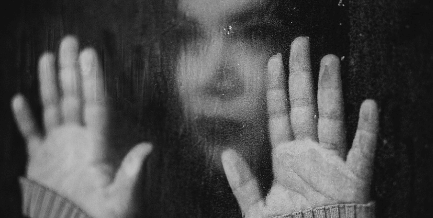 유리 창문에 손을 짚고 우울해 하고 있는 여성