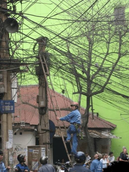 거미줄처럼 늘어져 있는 전기선을 확이하기 위해 사다리를 오르는 전기공들