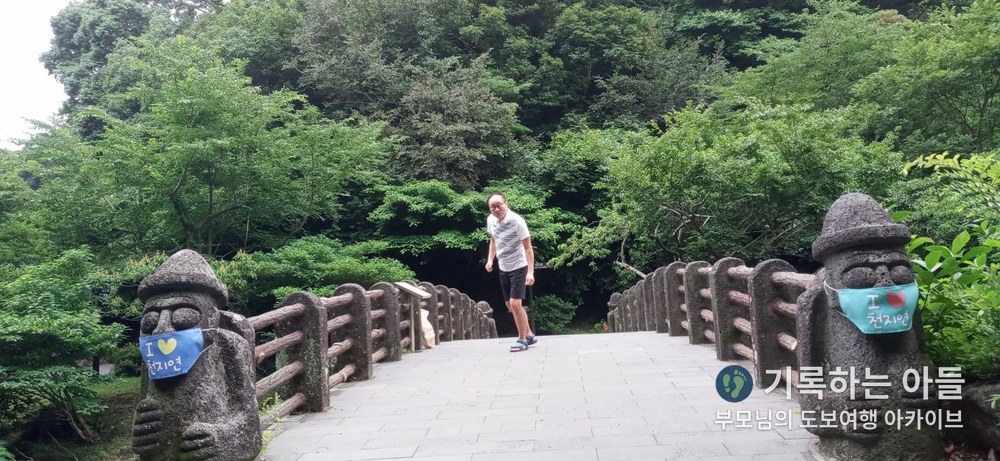 마스크를 쓴 돌하르방 한 쌍이 서 있는 돌다리