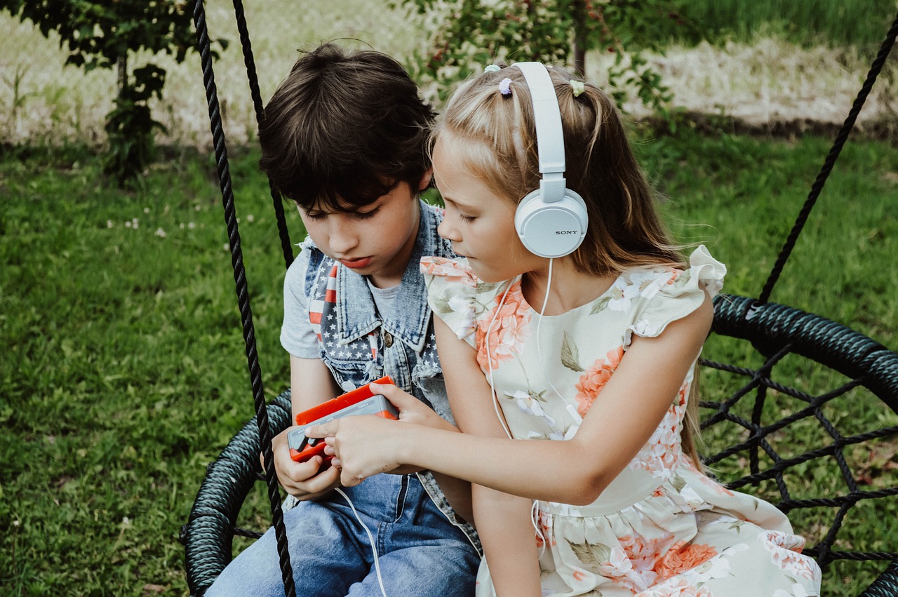 a girl wearing a headset showing a casset plyer to a boy next to her