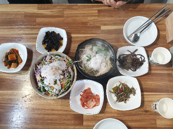 테이블위에 여러 반찬과 문어 회국수와 문어 국밥이 보인다.