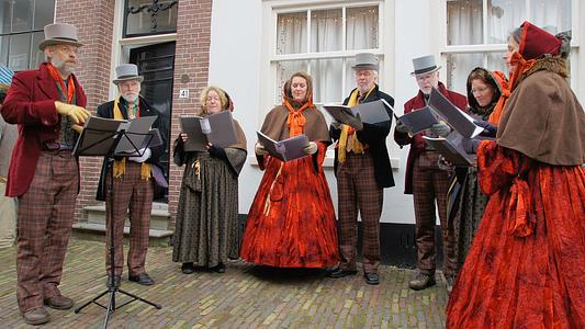 거리에서 캐럴을 노래하는 모습을 볼 수 있는 이미지입니다.