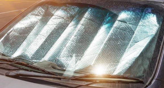 자동차 앞유리에 은박돗자리로 햇볕을 가리고 있는 사진