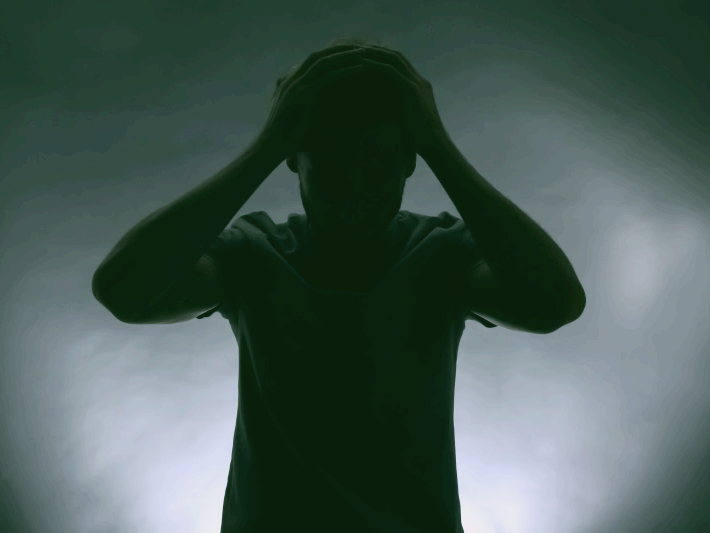 공황장애 증상 자가진단 치료 극복법에 관한 글의 이해를 돕기위한 이미지 : 남성으로보이는 사람의 실루엣 사진. 머리를 움켜쥔채 고개를 숙이고 있다.