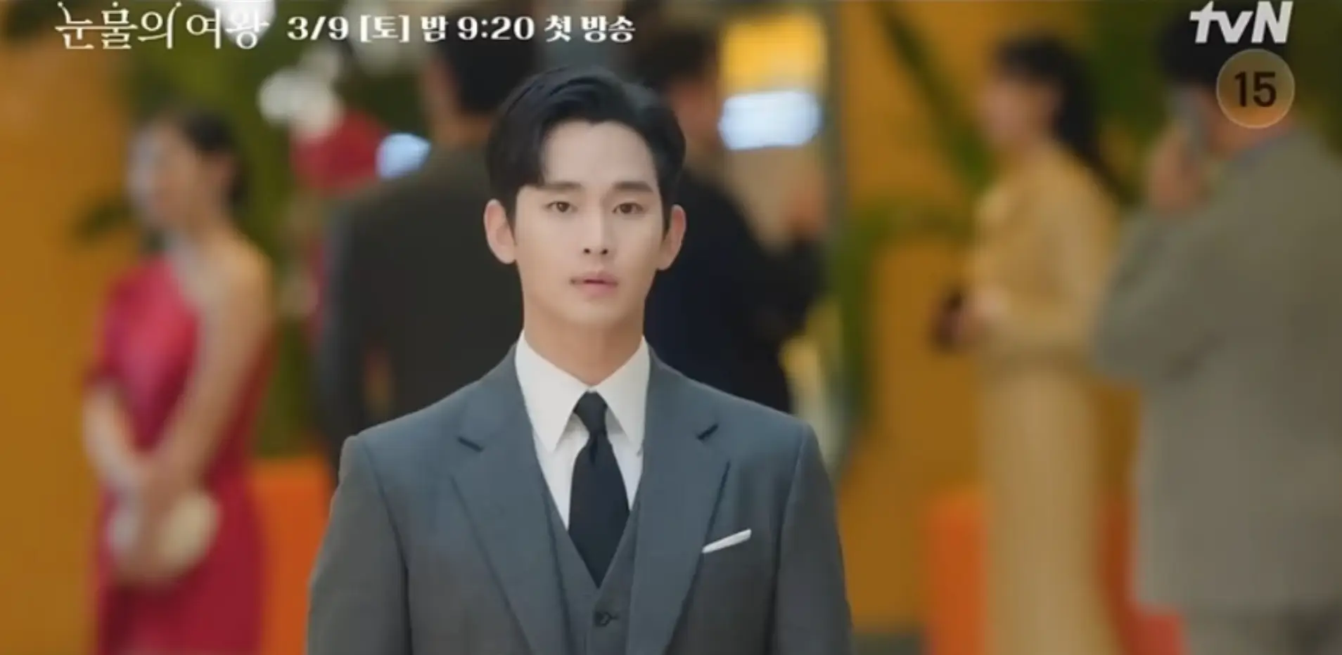 김수현- 사람들이 많은 파티장소 회색수트를 입고 정면을 바라보는 김수현