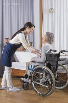 요양병원에서-휠체어를타고-움직이는-할머니를-요양보호사가-침대로-옮겨주려는-모습