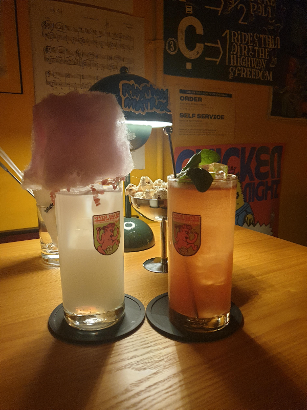 테이블 위에 두 잔의 칵테일이 올려져 있다. 왼쪽은 솜사탕이 올라가 있는 끼, 오른쪽은 바질이 올려져 있는 흥