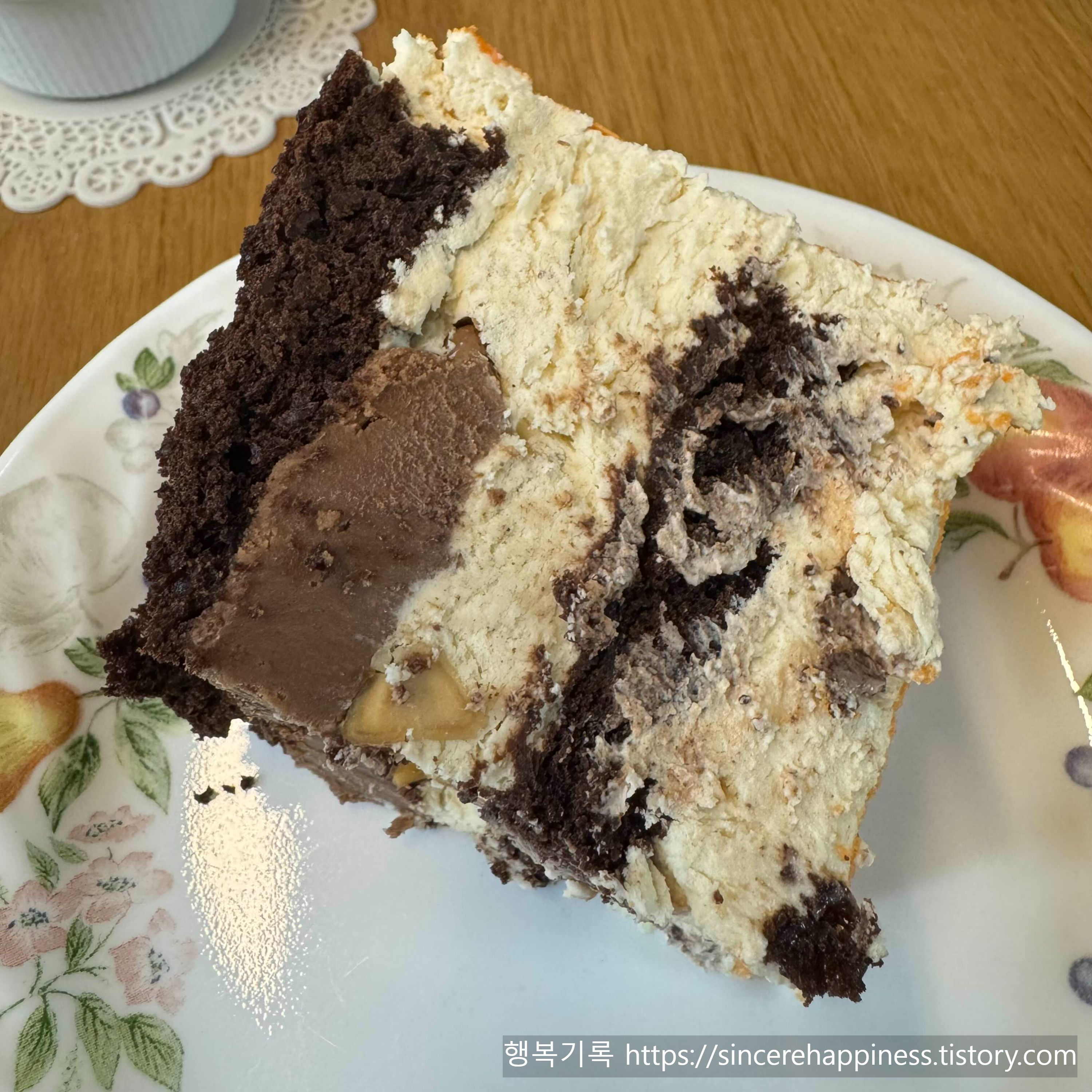 꾸덕한 헤이즐넛 초코 가나슈 층이 돋보이는 마카다미아 케이크 조각 금박 장식이 올라간 정사각 형태