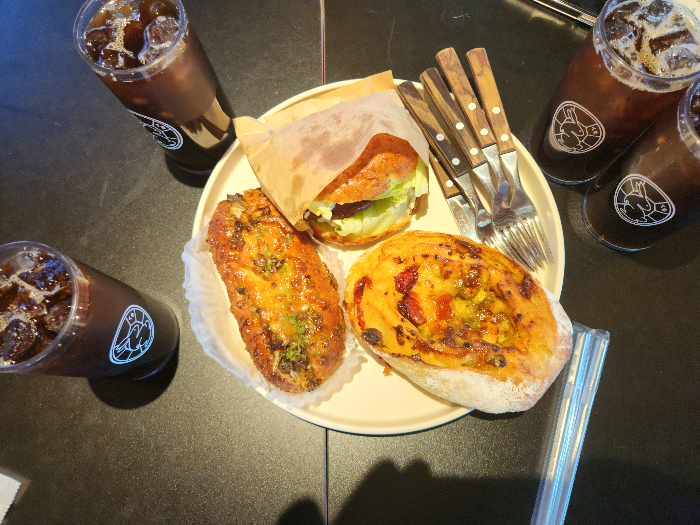 There are four cups of coffee and three pieces of bread on a plate on the table.
