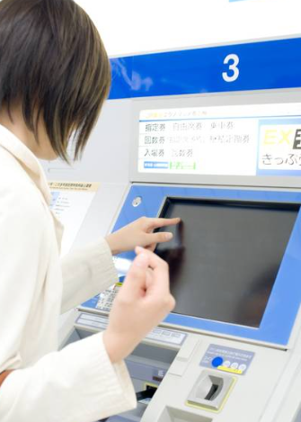 여성이 자동 판매기 앞에서 화면에 손가락을 대고 있다.