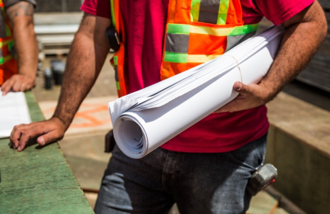 건설 근로자가 건축도면을 들고 있다.