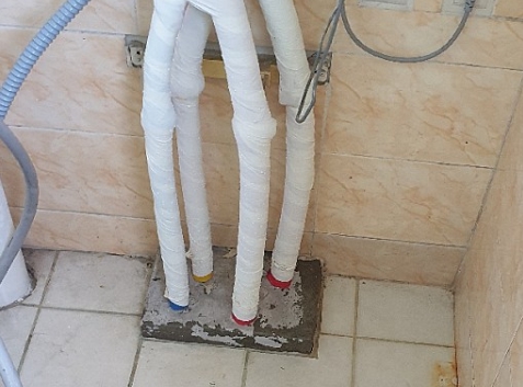 친환경 보일러 배수 공간을 찍은 사진으로 보일러 본체 하단에 호스와 배수구를 연결해 놓은 모습입니다.