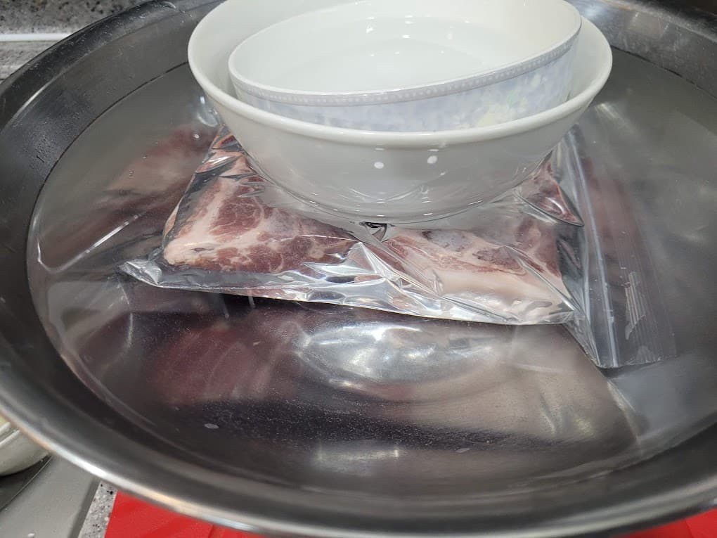 냉동 삼겹살이 소금물에 잠기도록 밀봉 후 무거운 그릇으로 고정