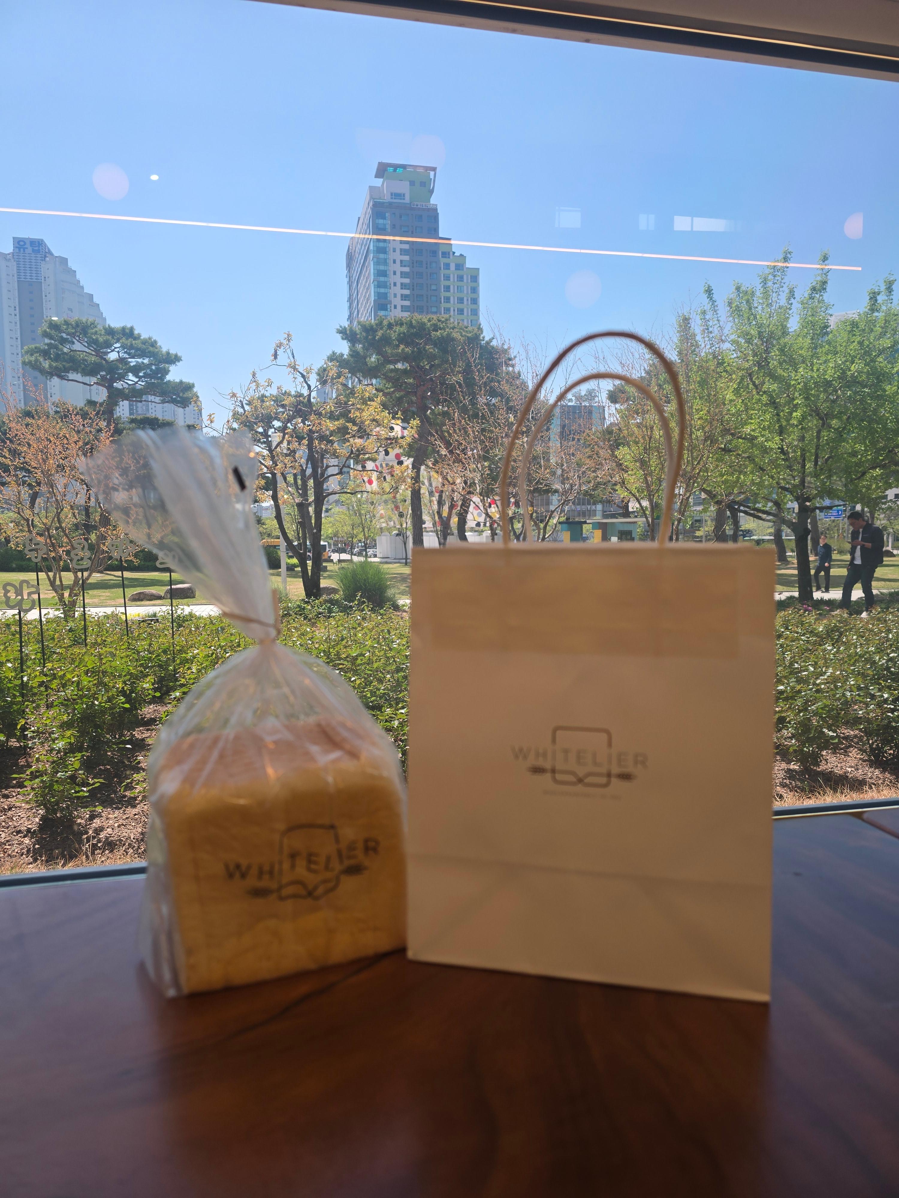 통유리창이 보이는 창가 테이블 위에 화이트리에 식빵이 올려있는 모습