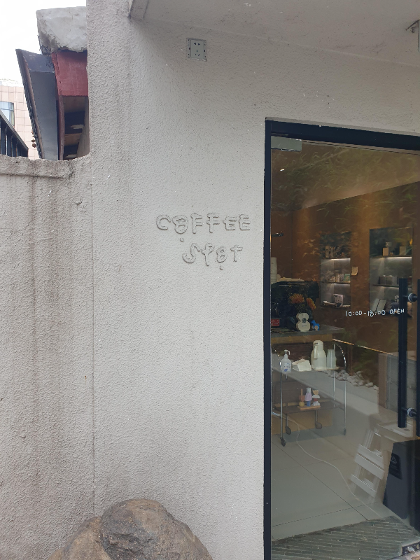 노출 시멘트 벽면에 양각으로 새겨진 커피스팟 간판