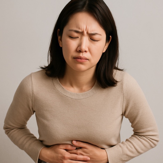 복통으로 괴로워하며 배를 움켜쥔 채 눈을 꼭 감고 있는 젊은 여성(출처: 자체제작)