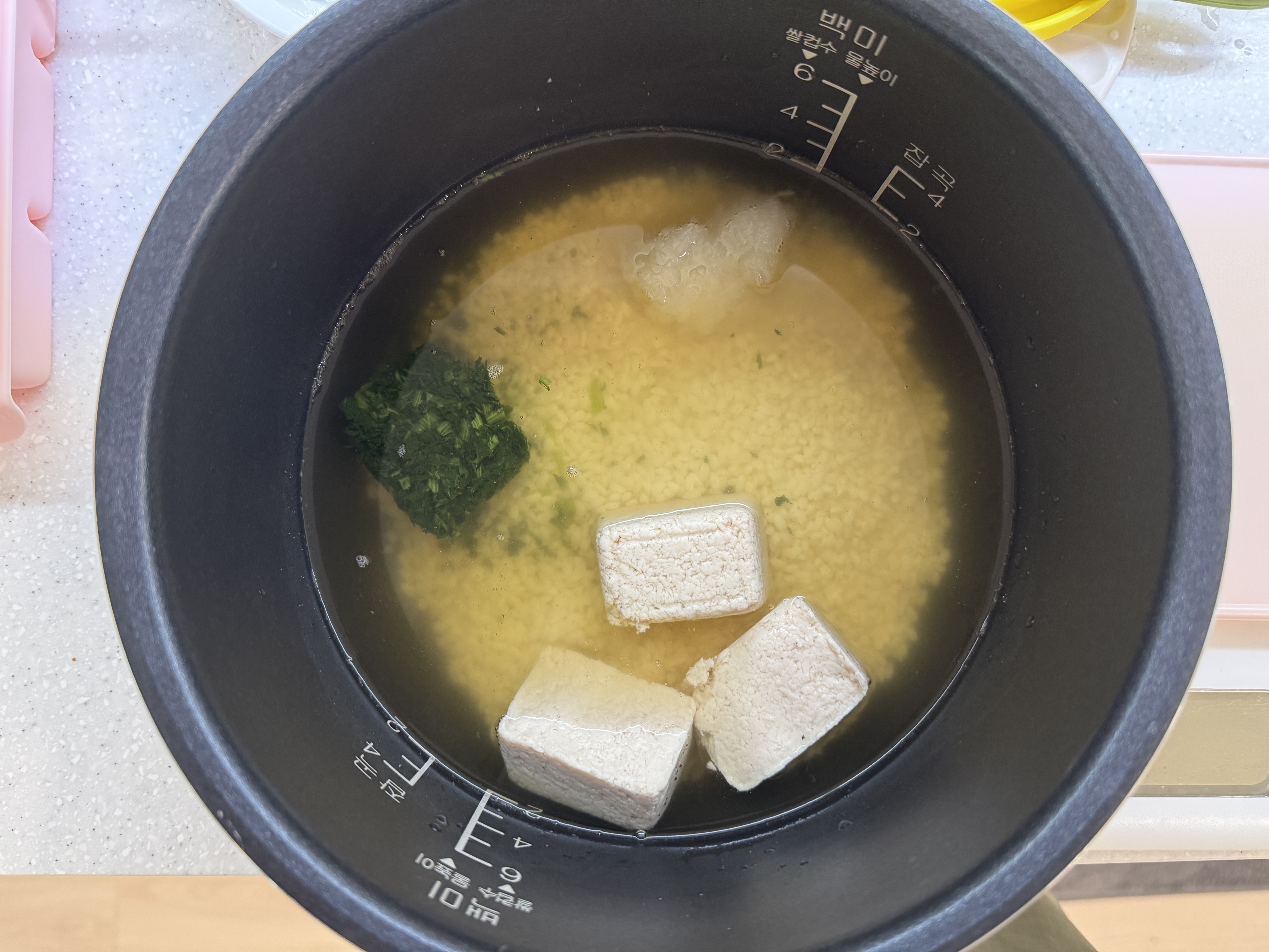 밥솥에 불린쌀&amp;#44; 채수&amp;#44; 닭고기 큐브&amp;#44; 비타민 채소큐브&amp;#44; 양파를 넣은 사진