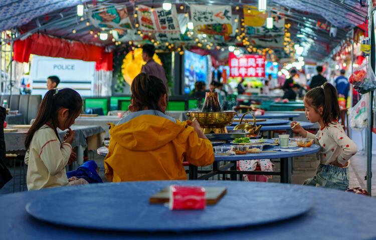 중국 청두의 환화시 야시장 안에서 어린이들이 훠궈를 먹으며 가족과 함께 저녁 시간을 보내는 활기찬 일상의 풍경