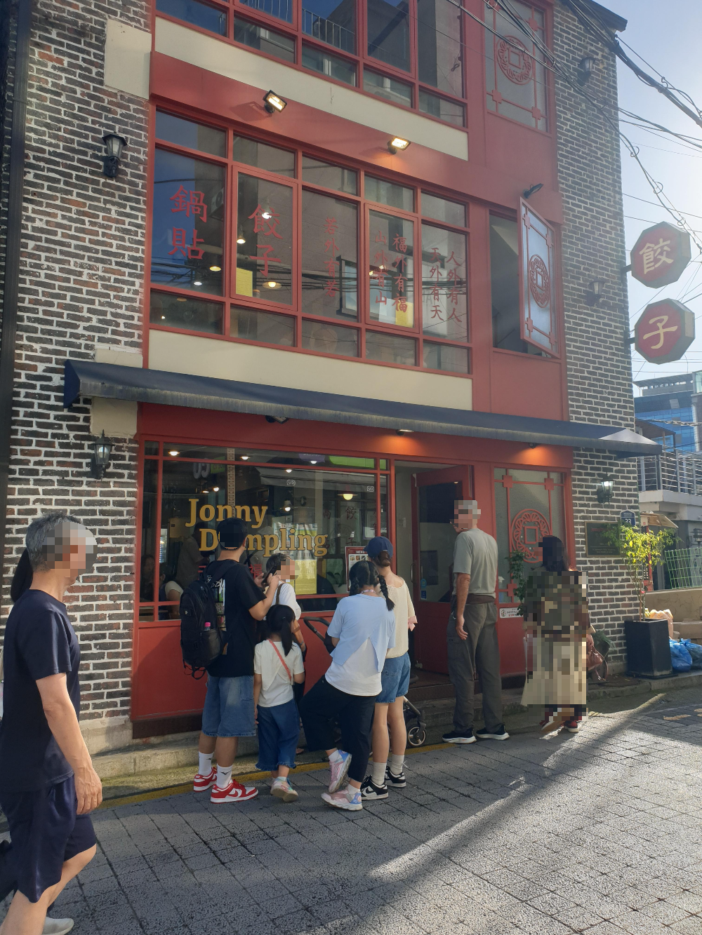 적색 별돌과 창틀이 인상적인 쟈니 덤플링 외관. 밖에 줄을 서고 있는 사람들이 보인다.