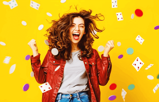 긴 갈색 파마머리 백인 여성이 주먹을 쥐고 팔을 반만 올리면서 환호한다. 주변엔 카드들이 떨어진다.