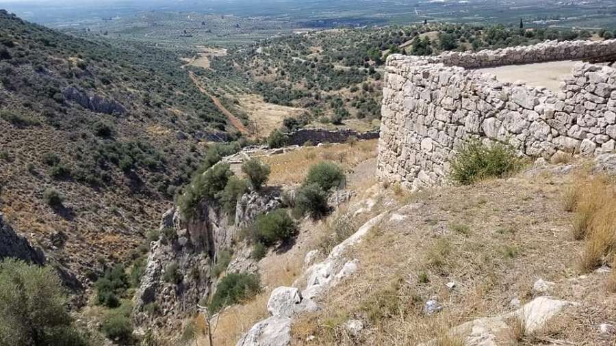 고대 미케네 성벽과 주변 산지&amp;#44; 계곡&amp;#44; 그리고 멀리 펼쳐진 평야를 보여주는 사진