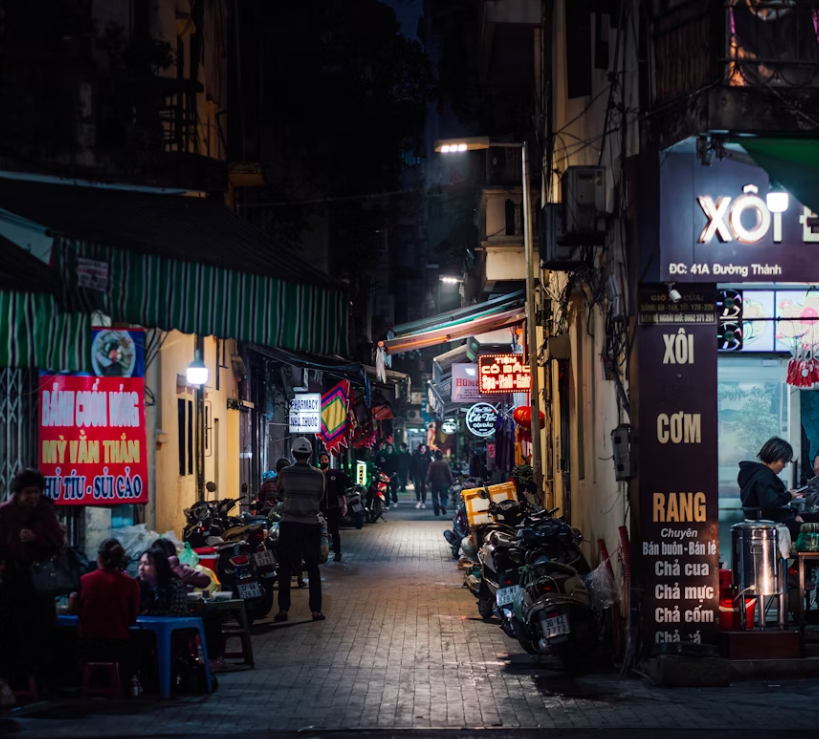 테이블에 앉아있는 사람들이있는 밤의 좁은 거리