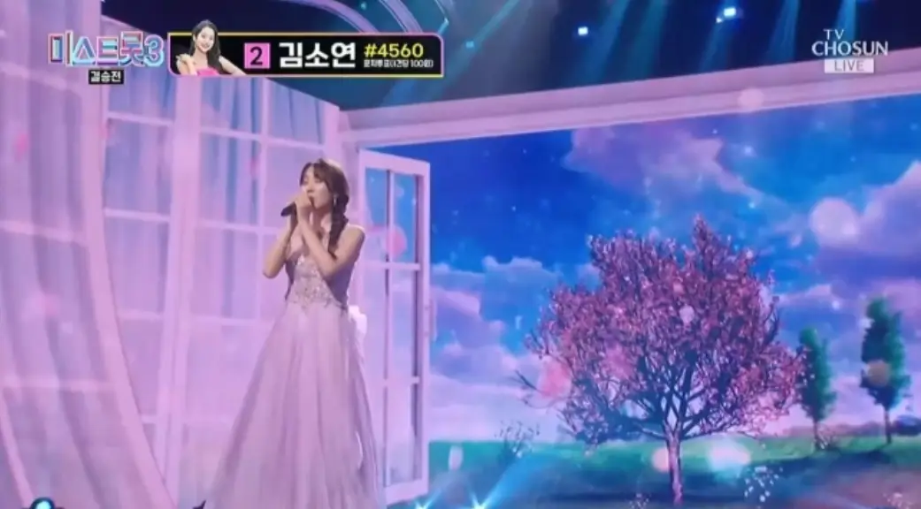 미스트롯3- 파란색 무대비경 보라색 나시 원피스 머리를 왼쪽으로 길게 땋아 두손으로 마이크를 든채 노래하는 정슬