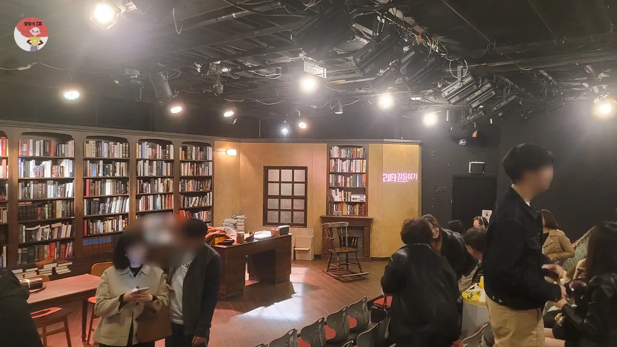 리타길들이기 연극이 끝난 무대와 객석&#44; 무대위에 다양한 책들이 가득한 서재가 보인다.