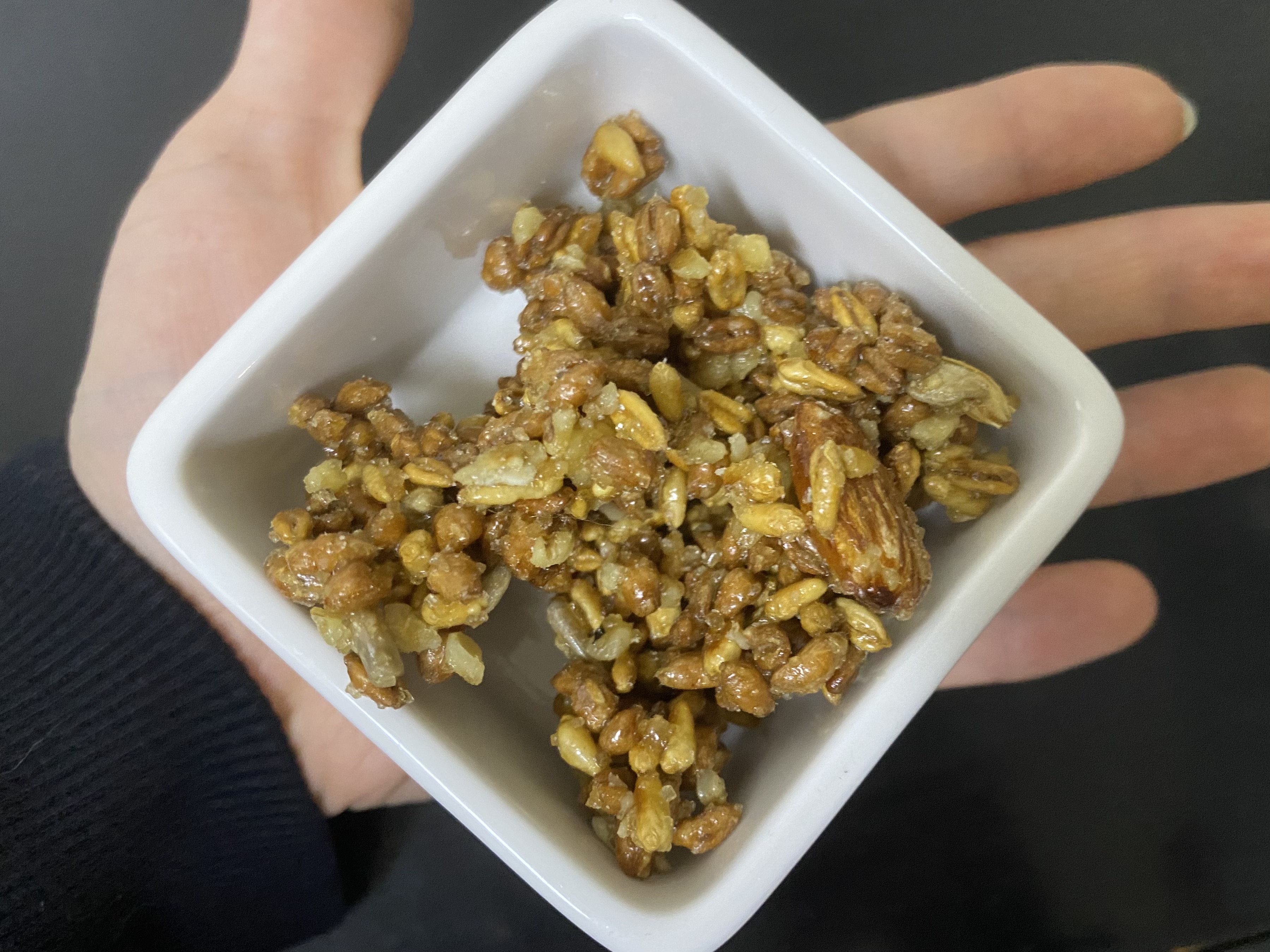 '그래놀라 파로이츠'를 25g 작은 흰색 그릇에 담은 사진입니다. 손바닥을 쫙 펴고 손바닥 위에 네모난 흰색 그릇을 올려놓은 사진입니다.