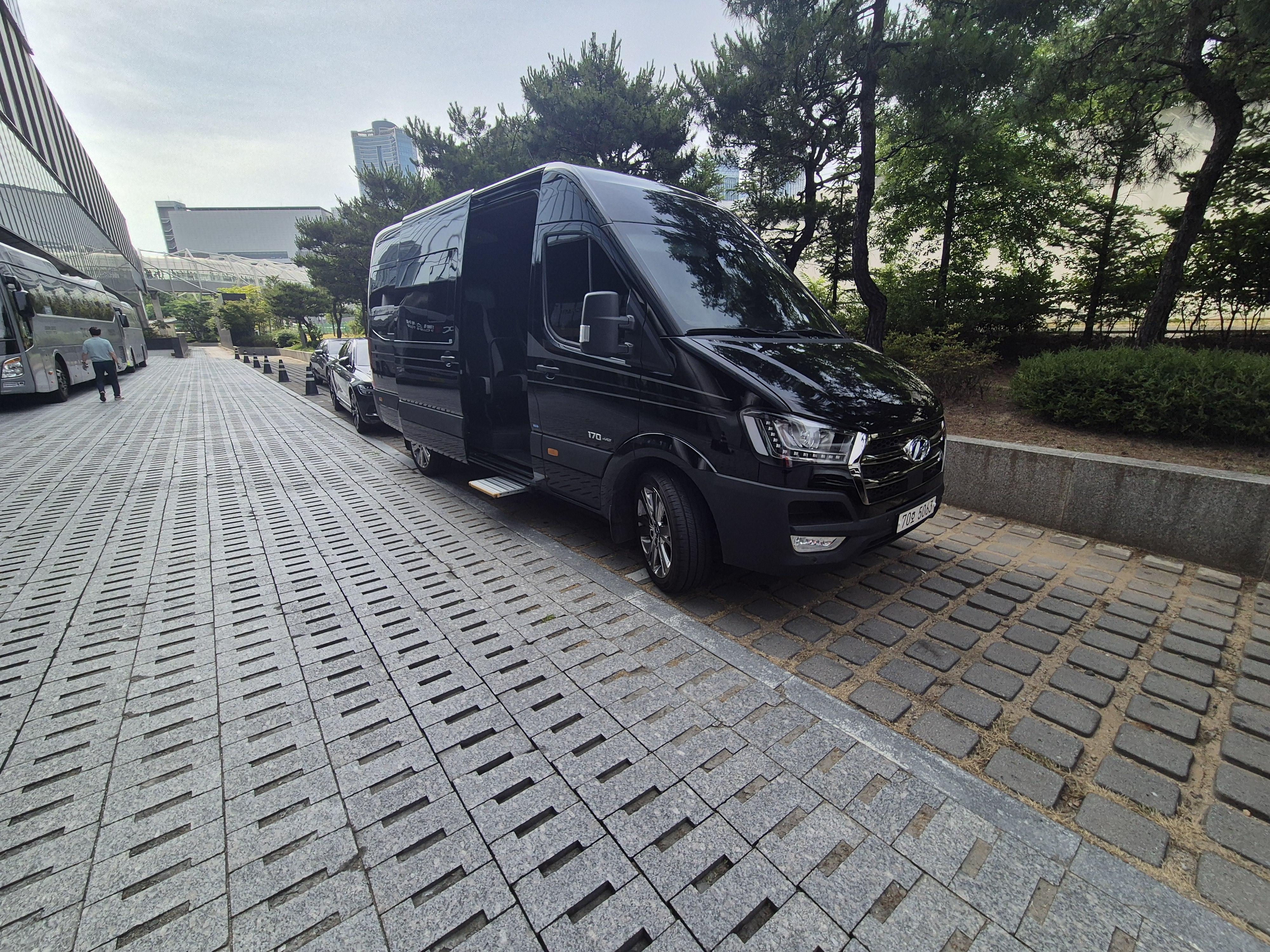 라티 15인승 미니버스 차량이 VIP 의전을 위해 공항 픽업 구간을 운행하는 모습을 담은 고급 실사 이미지.