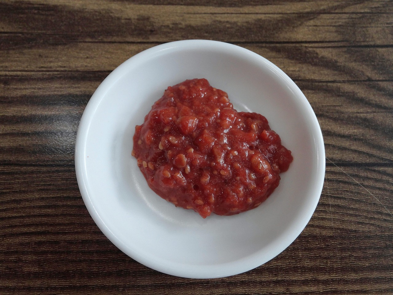 Traditional Korean ssamjang sauce served in a small white dish on a wooden table.