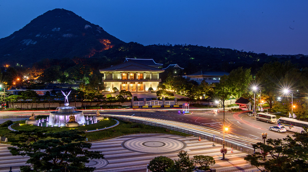 푸른 밤 남산아래 밝게 빛나는 청와대 건물과 분수대와 도로가 보인다.