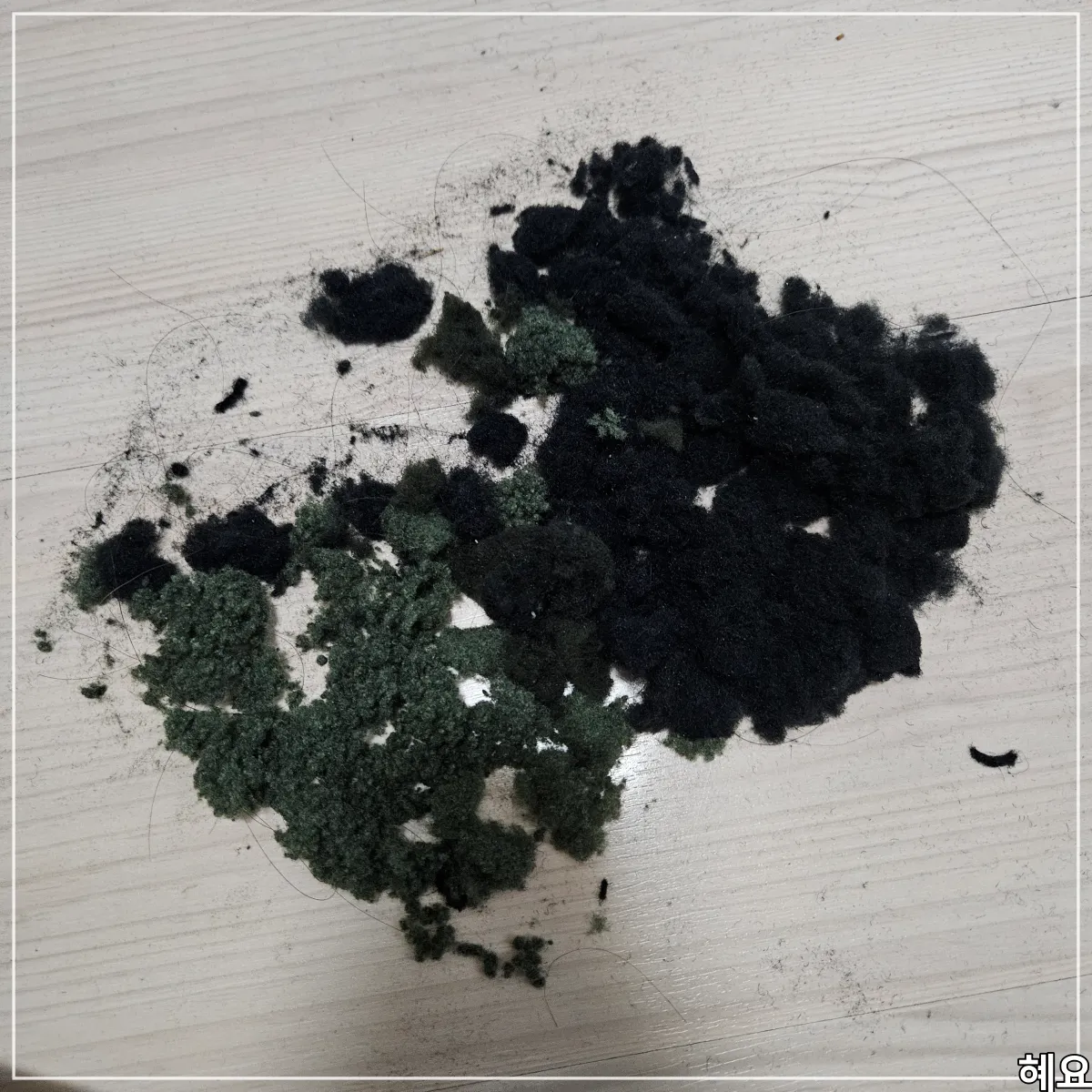 검은색-니트-멜리언스-보풀제거기-사용후기-바닥에-먼지가-가득-쌓여있다