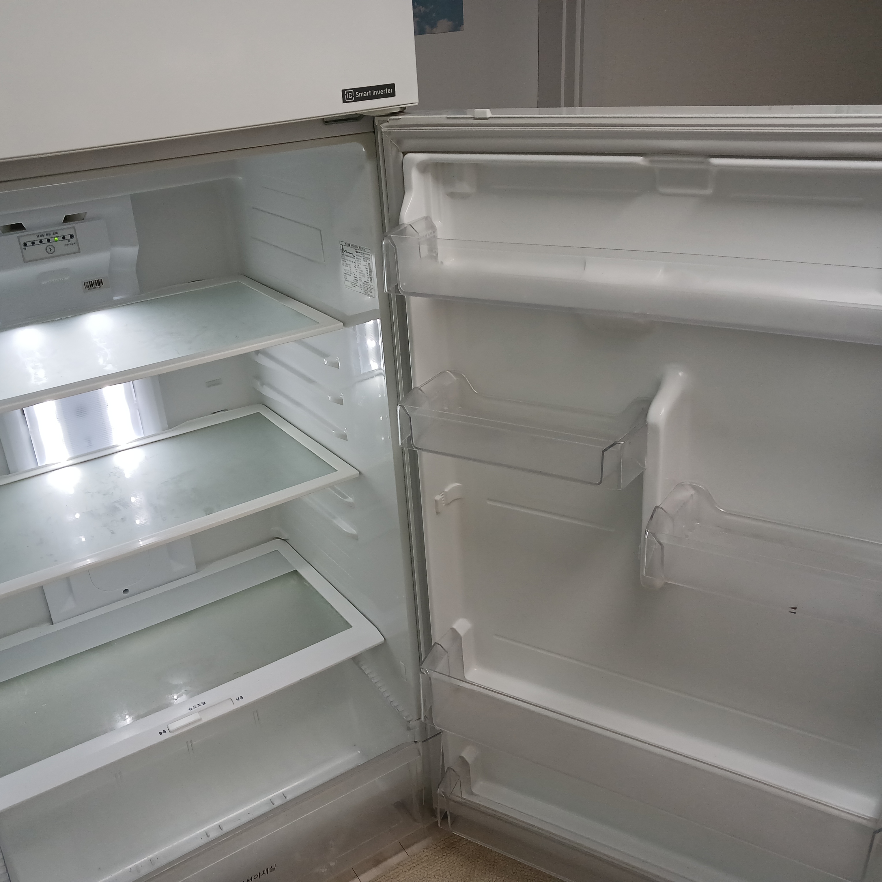 음식물을 모두 꺼내고 선반만 남은 텅 빈 냉장고 내부 모습