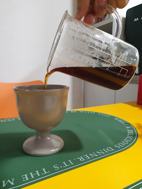 빈 잔에 추출된 커피를 따르는 모습이다.