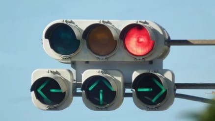 신호등에 붉은색 등이 들어와 있고 그 밑으로 파란색으로 왼쪽 위 오른쪽 방향의 신호에 불이 들어와 있다.