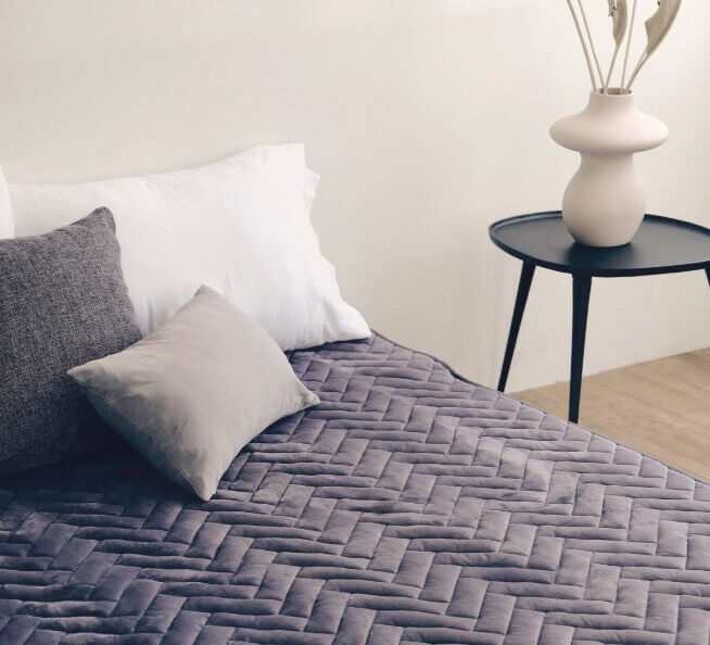 침대 위 회색 탄소매트와 베개 3개