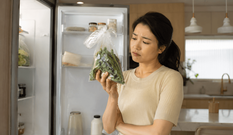 냉장고 열어 시든 채소 확인하는 여성