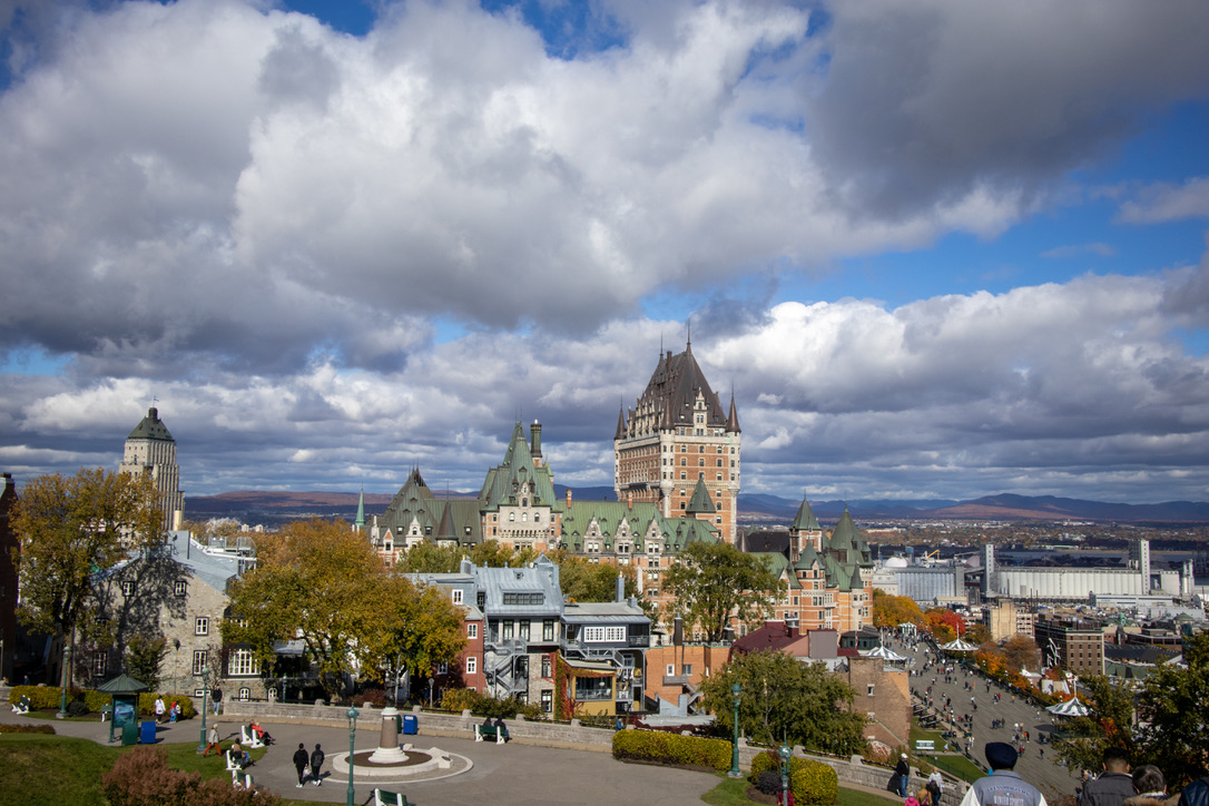 잔디밭에서 내려다본 퀘벡의 전경. 앞에는 민트색 지붕의 성처럼 생긴 호텔이 보인다. 하늘 사진이 2/3 이상 차지하고 있으며, 오른쪽 아래의 큰 도로로 엄청나게 작아 보이는 사람들이 걸어다니고 있다.