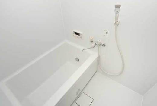 흰색 배경의 작은 화장실에 욕조와 샤워기가 있다