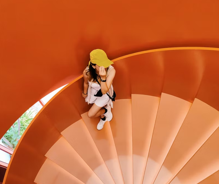 주황색 나선형 계단을 오르는 운동복 차림의 여성