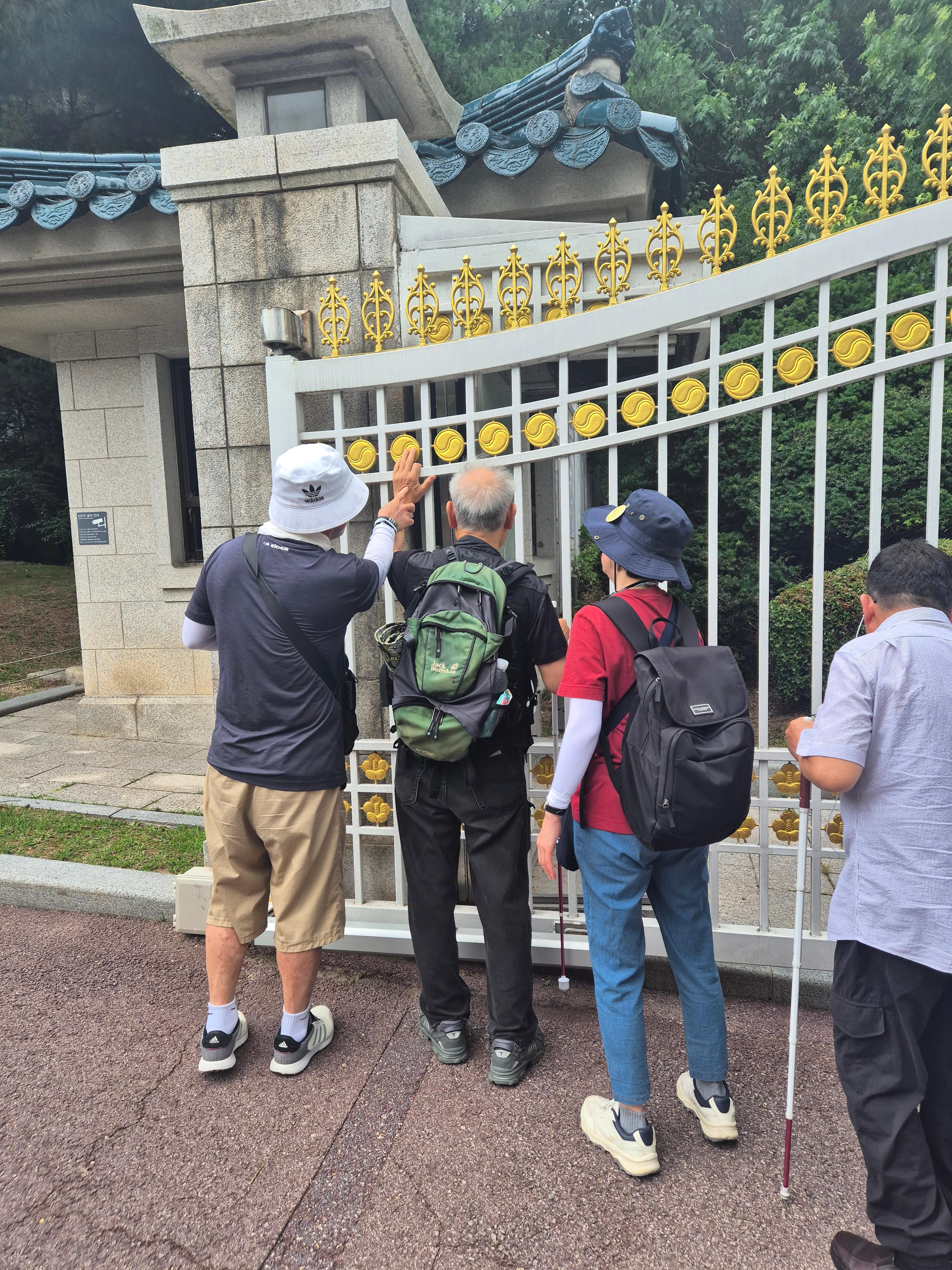 청와대 문에 있는 무궁화 모양을 지회원들이 직접 만져보는 모습