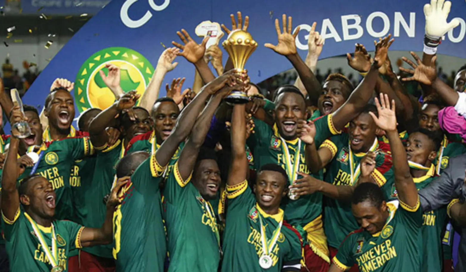 클린스만-황금색 우승컵을 들고 기뻐하는 초록색 유니폼을 입은 카메룬 선수들