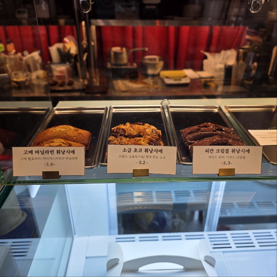 카페 쇼케이스에 진열된 휘낭시에 3종, 버터 바닐라&middot;소금 초코&middot;피칸 크럼블 디저트