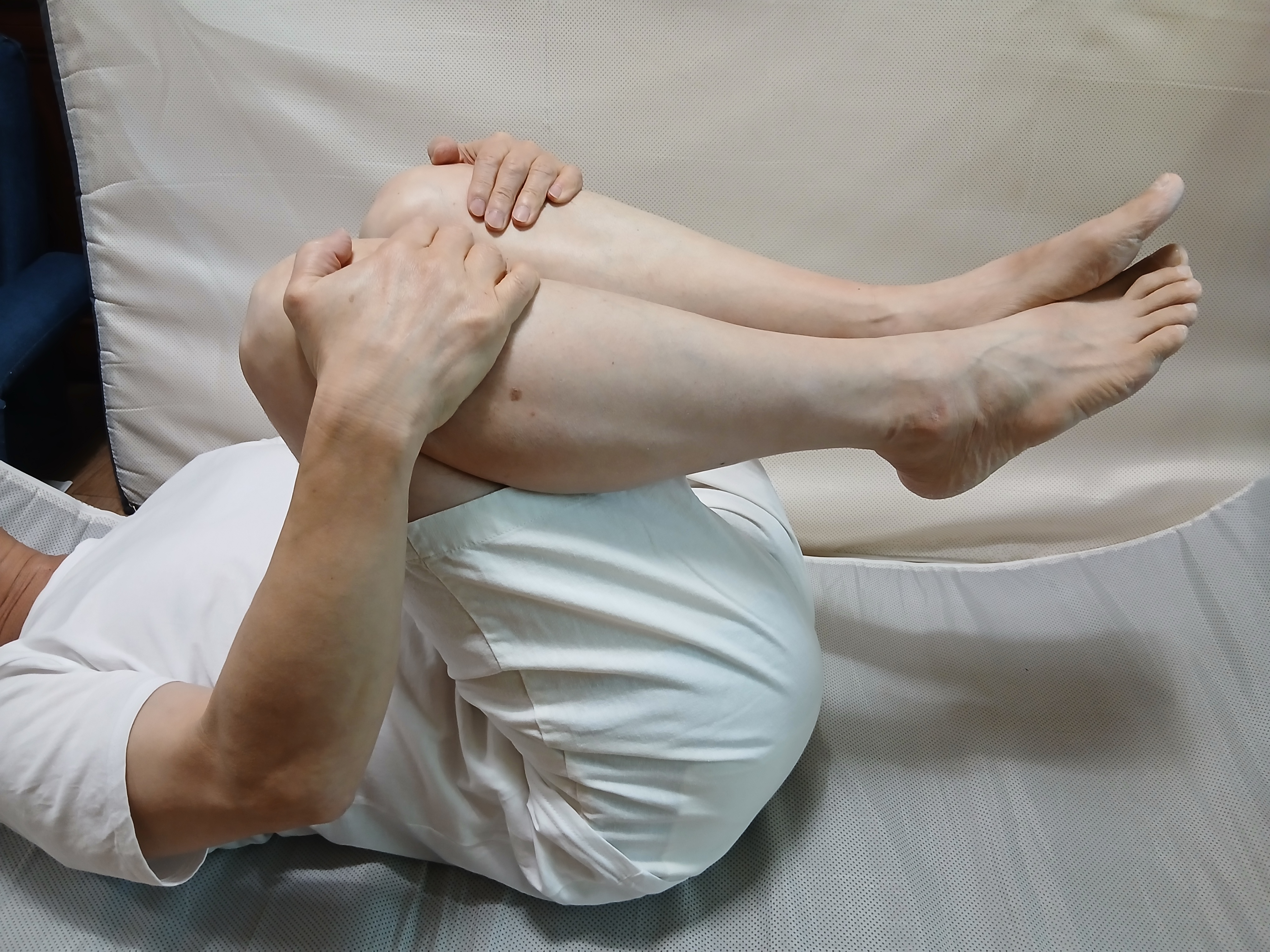 척추 마디 마디를 넓혀주는 효과가 있는 '바닥에 누워 양 무릎을 가슴 쪽으로 끌어당겨 양손으로 감싸는 이미지